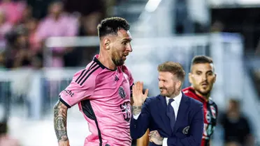 Lionel Messi is running with the ball with an Inter Miami jersey and David Beckham smiles and waves with a suit on. (Source: 433 X, The Independent)