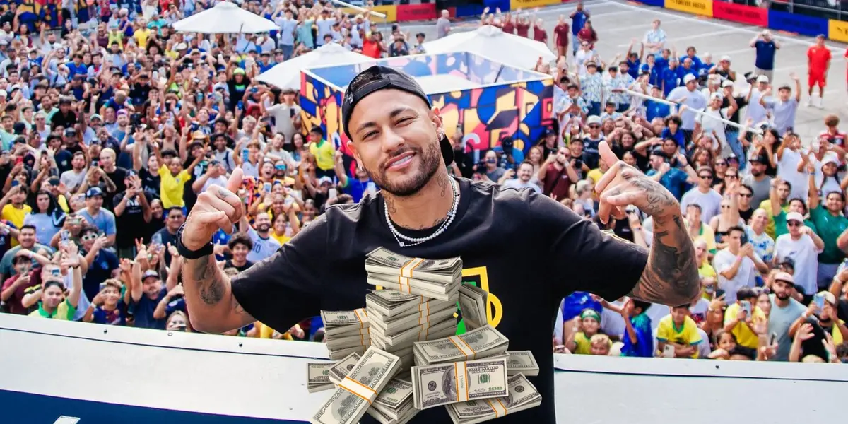 Neymar poses for a picture with hundreds of fans behind him and a stack of money in front of him. (Source: Team Ney 10 X)